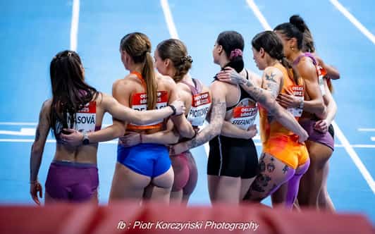 Sześć zawodniczek stoi objętych na bieżni lekkoatletycznej, odwróconych tyłem do aparatu.