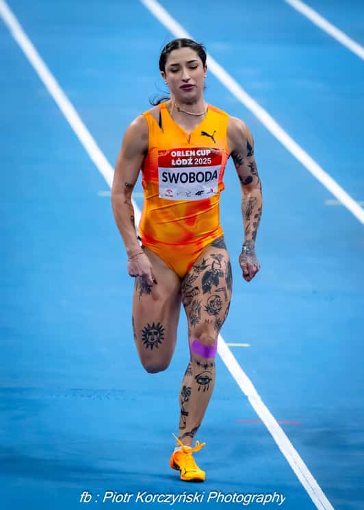 Biegaczka z numerem SWOBODA biegnie po niebieskiej bieżni podczas zawodów lekkoatletycznych.
