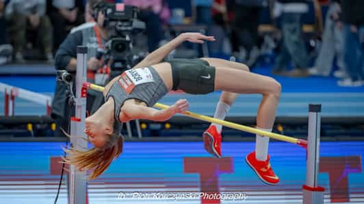 Zawodniczka pokonuje poprzeczkę w skoku wzwyż na hali lekkoatletycznej.